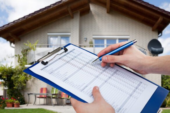 Vacation rental property inspection - a pair of hands holding a blue clipboard and pen in front of a house