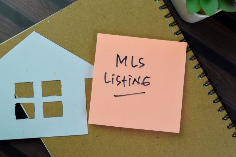 "MLS Listing" written on a sticky note beside a paper house