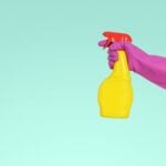 Hand with pink glove and yellow spray bottle for cleaning